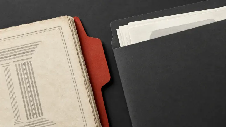 An older ivory code-pattern folio sits outside a new charcoal employment folder